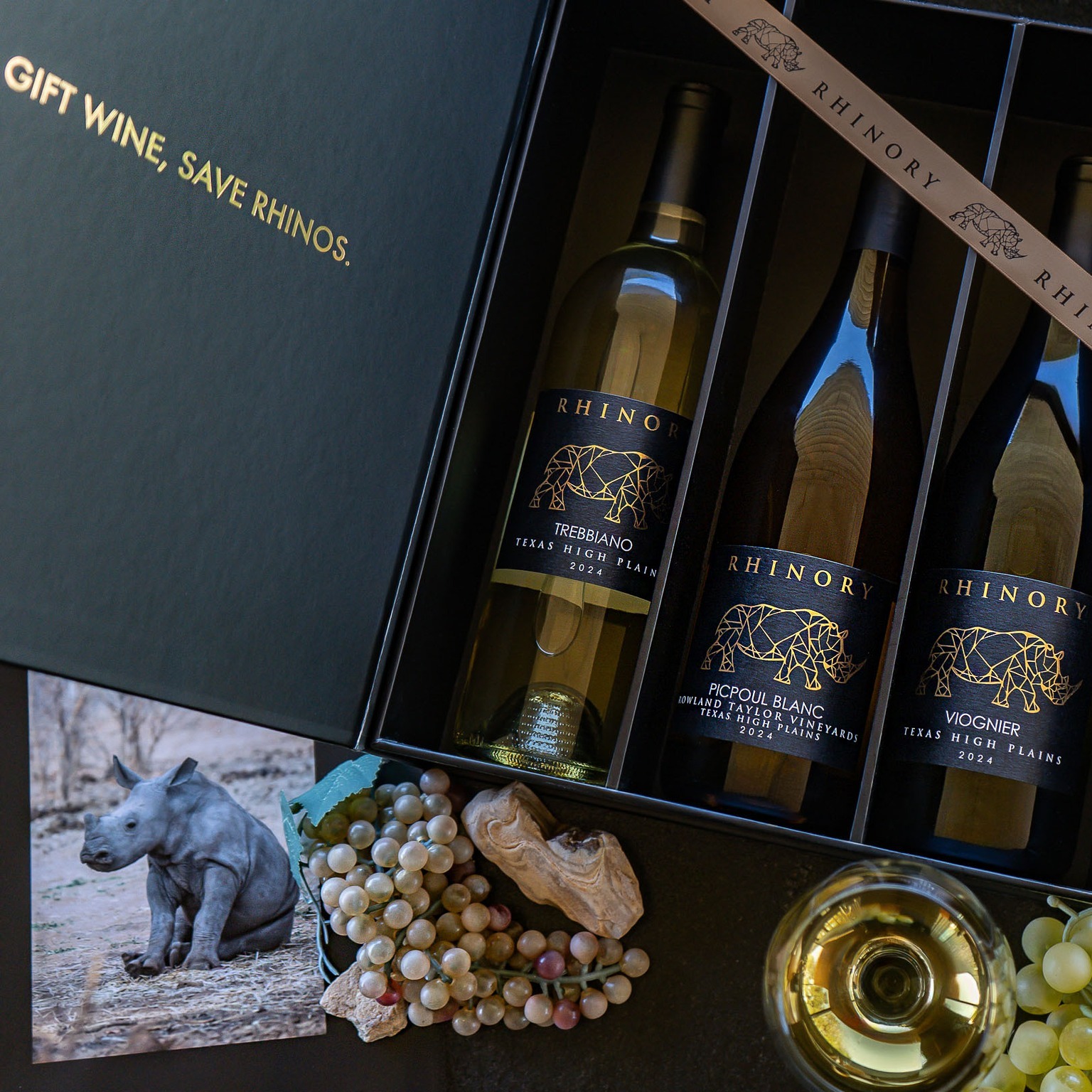 An open Rhinory gift box holding three bottles, the lid foiled in gold