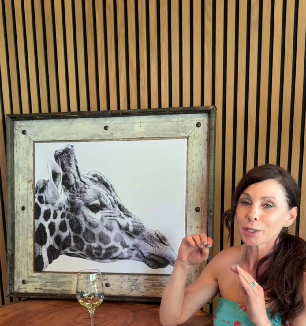Wanda Goldberg with a framed animal painting from the Wanda's Wee Zoo collection