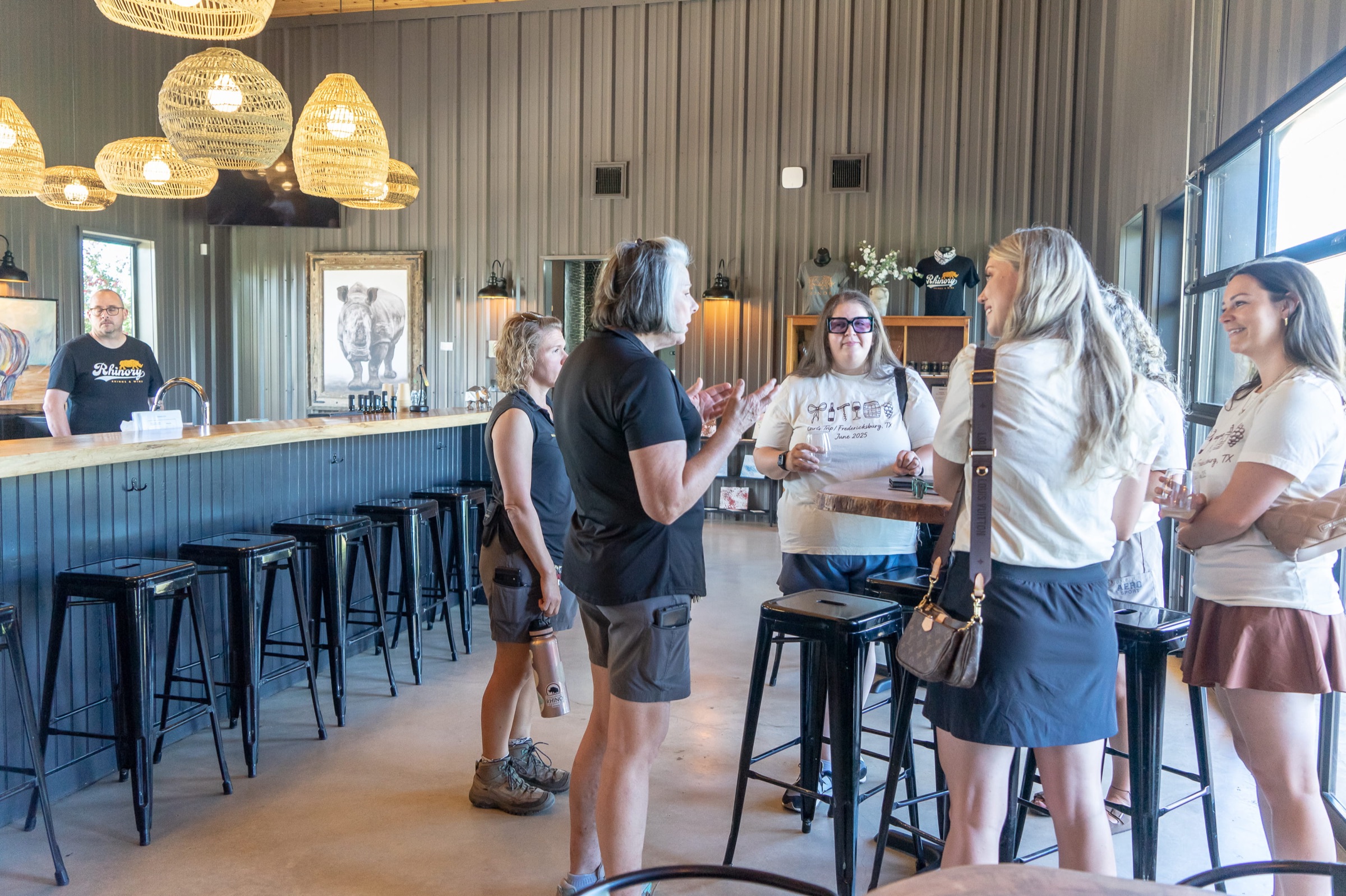 Wine educators pouring for guests at the tasting room bar under rattan pendant lights